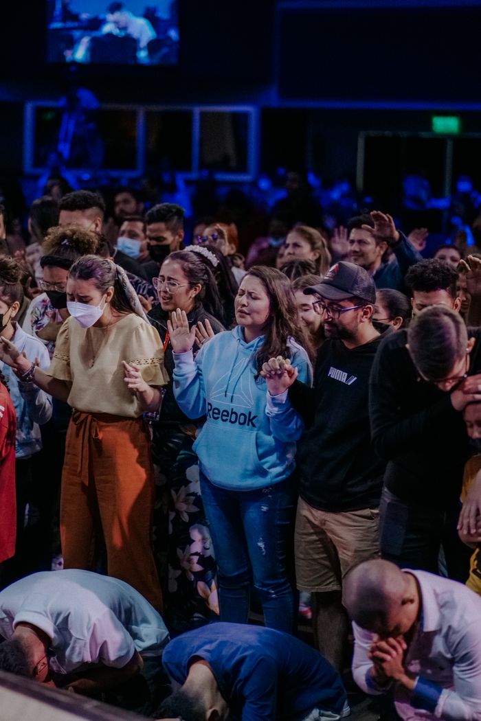 Large congregation standing and praying together inside a church.