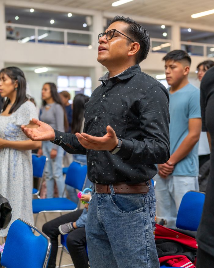 delivery-policy A group of diverse individuals engaged in prayer at a church in Mexico City, showcasing community and faith.